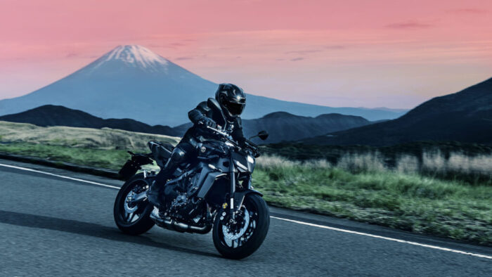 Yamaha MT-09 Y-AMT 2025 v gorski pokrajini ob sončnem zahodu, agresiven hyper naked dizajn in Y-AMT avtomatski sistem prestavljanja.