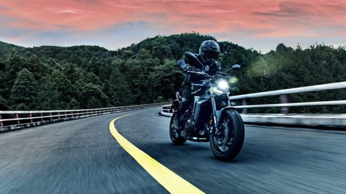 Yamaha MT-09 Y-AMT 2025 v vožnji skozi zavoj, stabilen aluminijast okvir in napredni elektronski sistemi za nadzor vožnje.