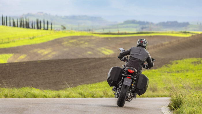 Yamaha Tracer 7 GT pogled od zadaj med vožnjo po ovinkasti cesti, GT različica s stranskimi kovčki
