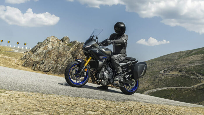 Yamaha Tracer 7 GT Y-AMT 2026 ustavljena na razgledni točki v gorah, Sport Touring motocikel z visokim vetrobranom in GT opremo za dolga potovanja.