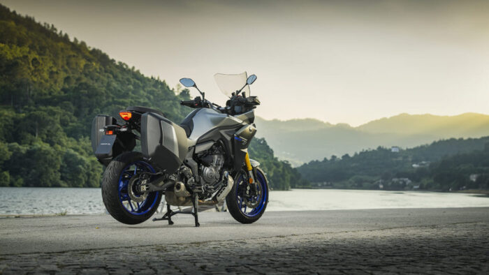 Yamaha Tracer 7 GT Y-AMT 2026 pogled od zadaj ob jezeru, GT različica s kovčki, LED zadnjo lučjo in stabilnim podvozjem.