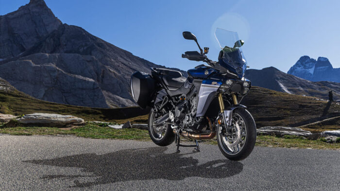 Yamaha Tracer 9 GT+ Y-AMT 2025 v alpskem okolju, 3/4 pogled spredaj z nameščenimi stranskimi kovčki