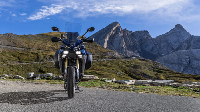 Yamaha Tracer 9 GT+ Y-AMT 2025 pogled spredaj z osvetljenimi matričnimi LED žarometi v gorah
