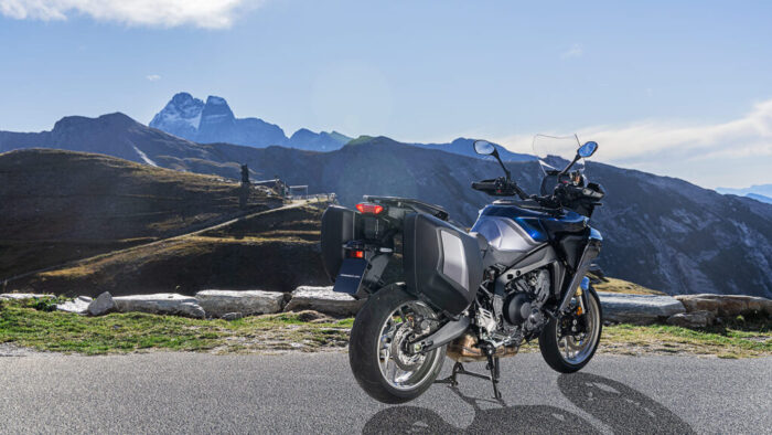 Yamaha Tracer 9 GT+ Y-AMT 2025 zadnji 3/4 pogled z integriranimi stranskimi kovčki in panoramskim gorskim razgledom