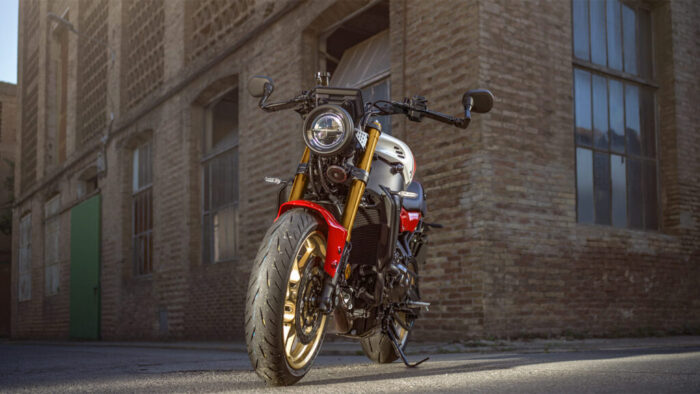 Yamaha XSR900 parkirana pred industrijsko stavbo, klasičen okrogel žaromet in zlata platišča v slogu heritage