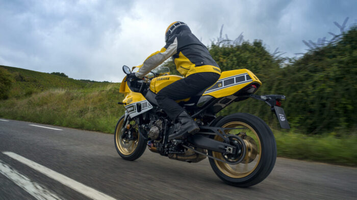 Yamaha XSR900 GP 2026 Legend Yellow v nagibu skozi ovinek – športna vožnja z dirkaško ergonomijo in vrhunskim vzmetenjem.