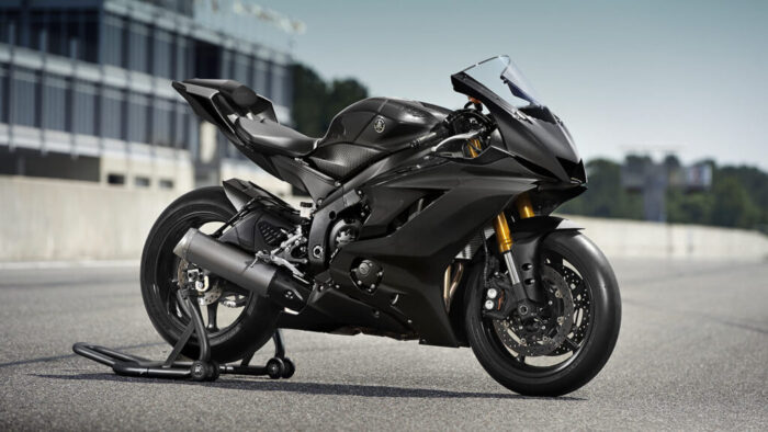 Yamaha R6 Race na stojalu ob stezi – minimalistična, osredotočena, pripravljena na akcijo. Odkrij jo od blizu.