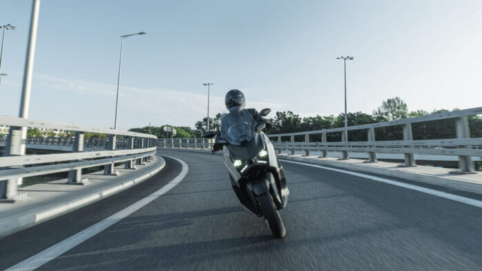 Yamaha XMAX 300 Tech MAX v nagibu skozi ovinek – stabilen sport skuter z izrazitim LED podpisom.