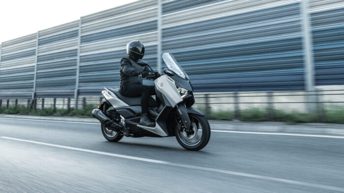 Yamaha XMAX 300 Tech MAX+ v gibanju, profilna silhueta poudarja dinamično obliko ohišja in zmogljiv 300 cm³ agregat – popolna kombinacija športa in vsakodnevne praktičnosti.