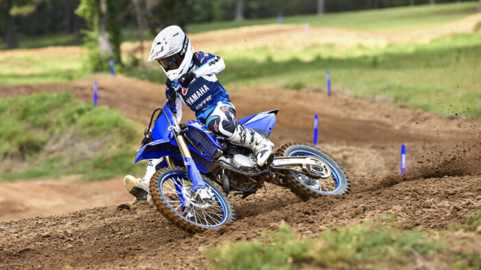 Yamaha YZ85 2026 med vožnjo skozi ovinek na motokros stezi z dvignjenim peskom